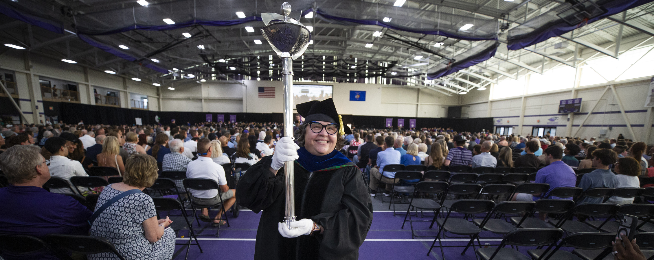 Kim Kostka dances with the ceremonial mace during commencement.