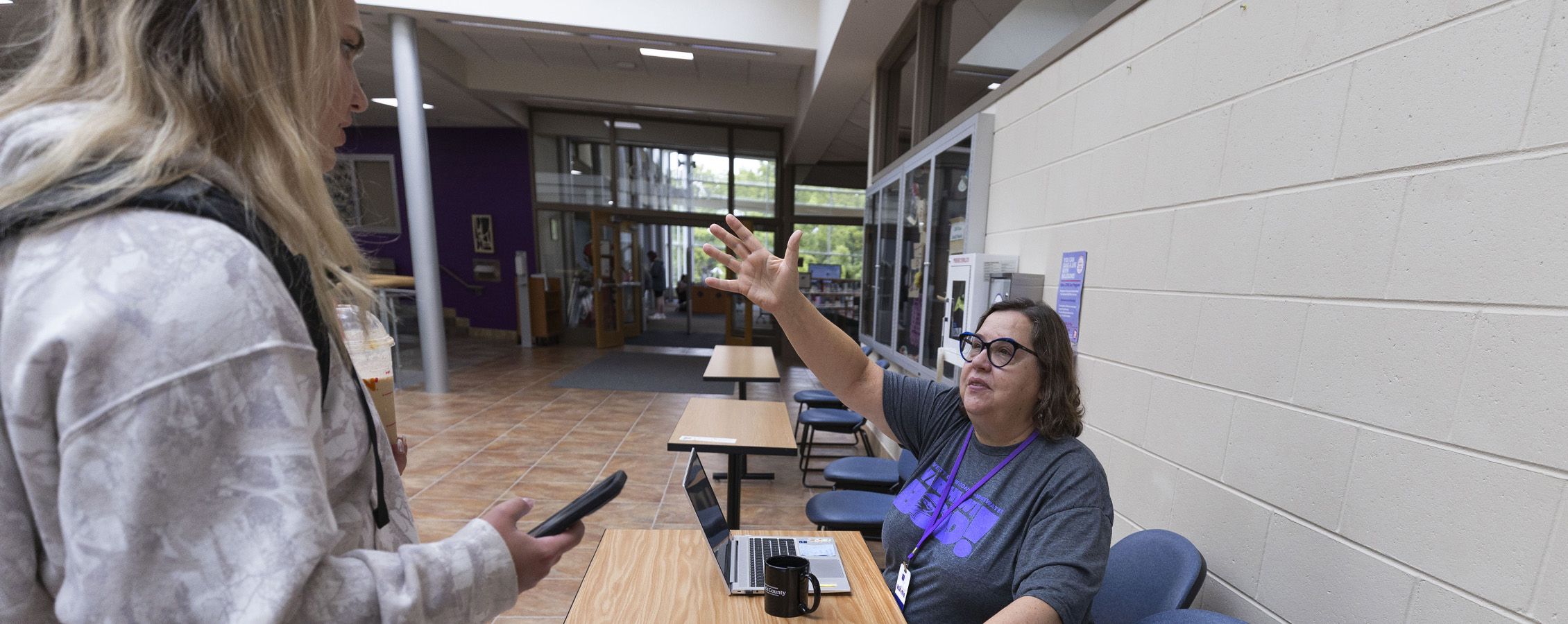 Kim Kostka points while giving a student directions inside a university building.