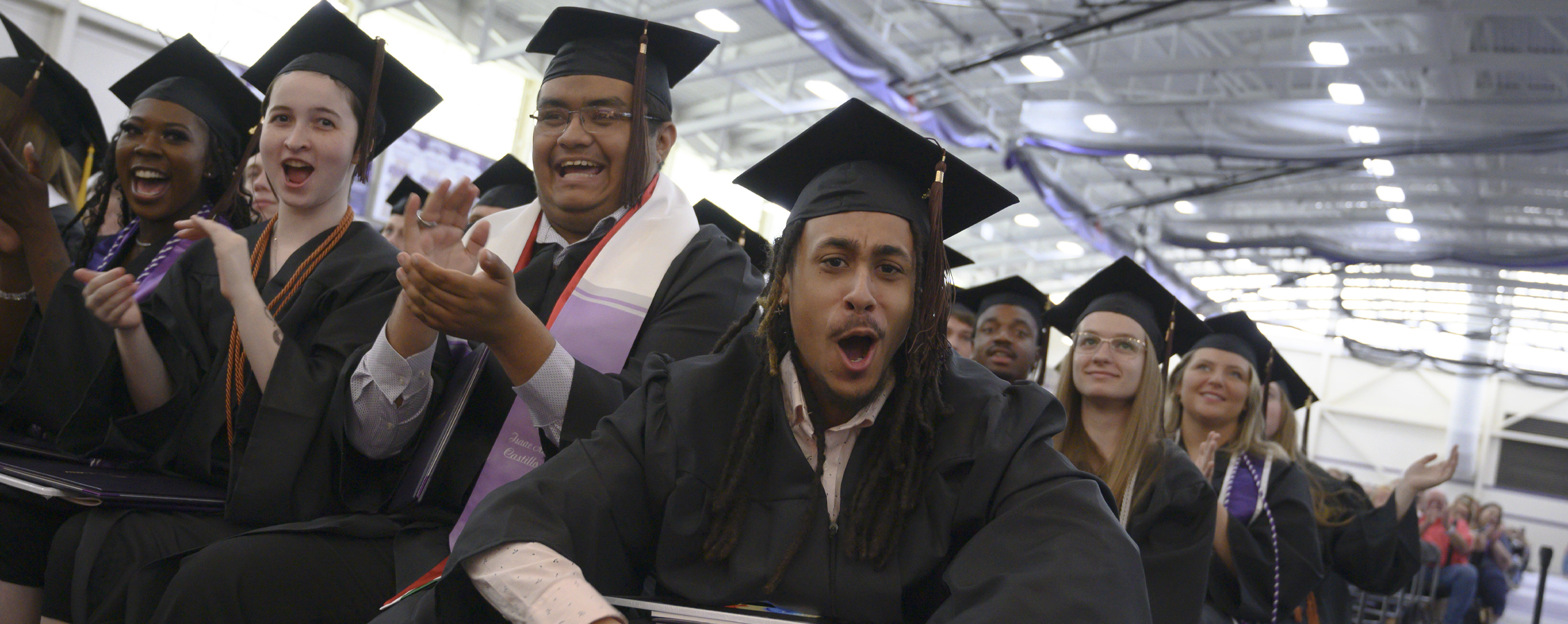 Graduates clap and cheer during commencement.