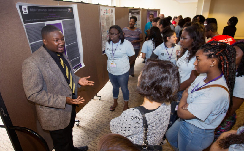 Kyree Brooks speaks to a small crowd of people during undergraduate research.