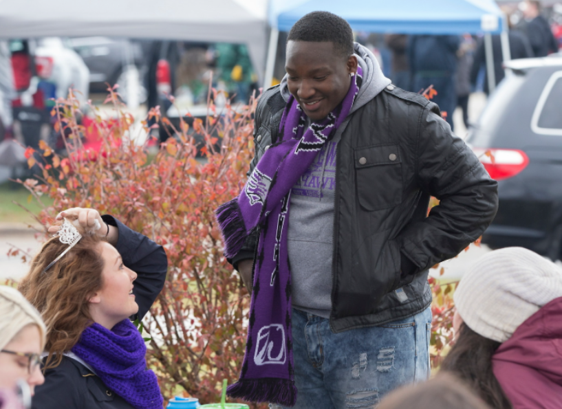 Kyree Brooks wears a purple UW-Whitewater scarf while chatting with another person.