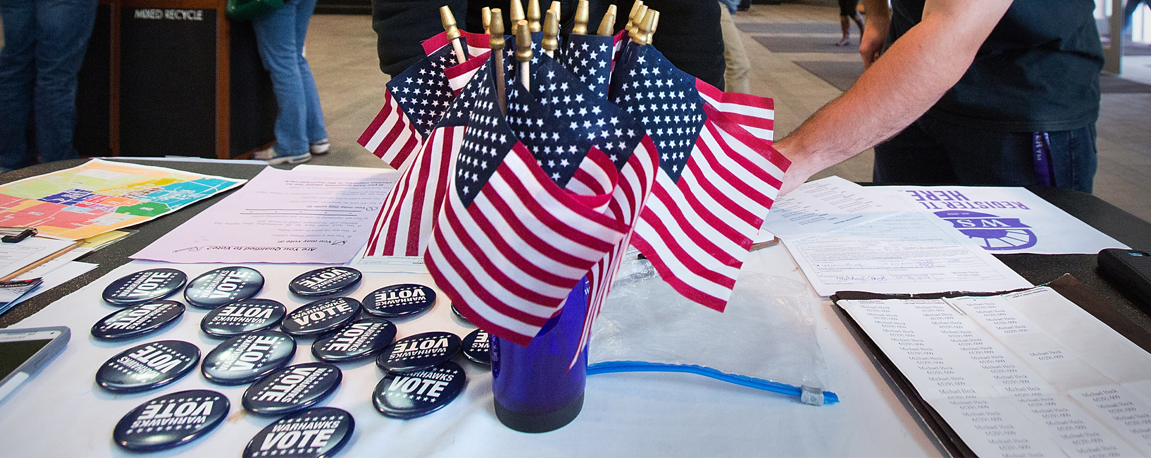 American flags and Warhawks Vote buttons sit on a table.
